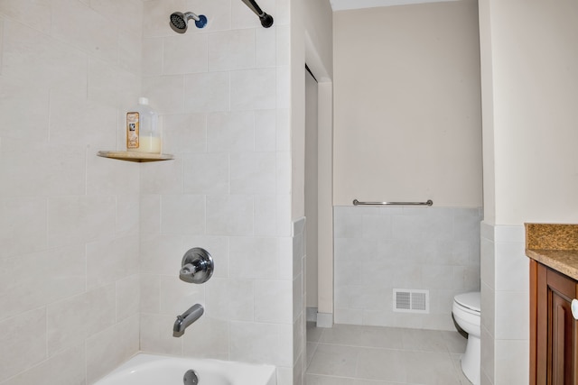 full bathroom featuring tiled shower / bath, tile walls, vanity, toilet, and tile patterned floors