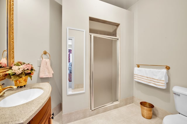 bathroom with a shower with door, vanity, tile patterned floors, and toilet