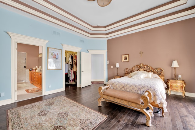 bedroom featuring dark wood-type flooring, connected bathroom, ornamental molding, a spacious closet, and a closet