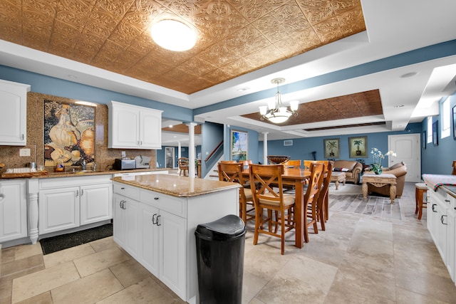 kitchen with a center island, decorative light fixtures, white cabinets, and a tray ceiling