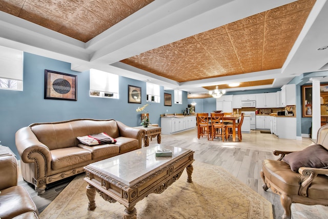 living room with a raised ceiling, light wood-type flooring, and a notable chandelier