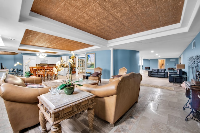 living room featuring a tray ceiling and ornate columns