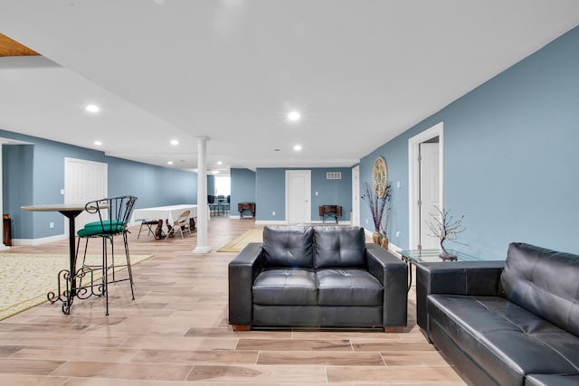 living room with decorative columns and light hardwood / wood-style flooring