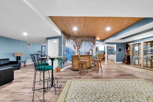 bar with light hardwood / wood-style flooring and decorative columns