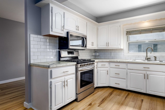 kitchen featuring sink, white cabinetry, light hardwood / wood-style flooring, appliances with stainless steel finishes, and decorative backsplash