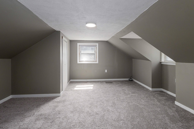 bonus room with vaulted ceiling, a textured ceiling, and carpet flooring