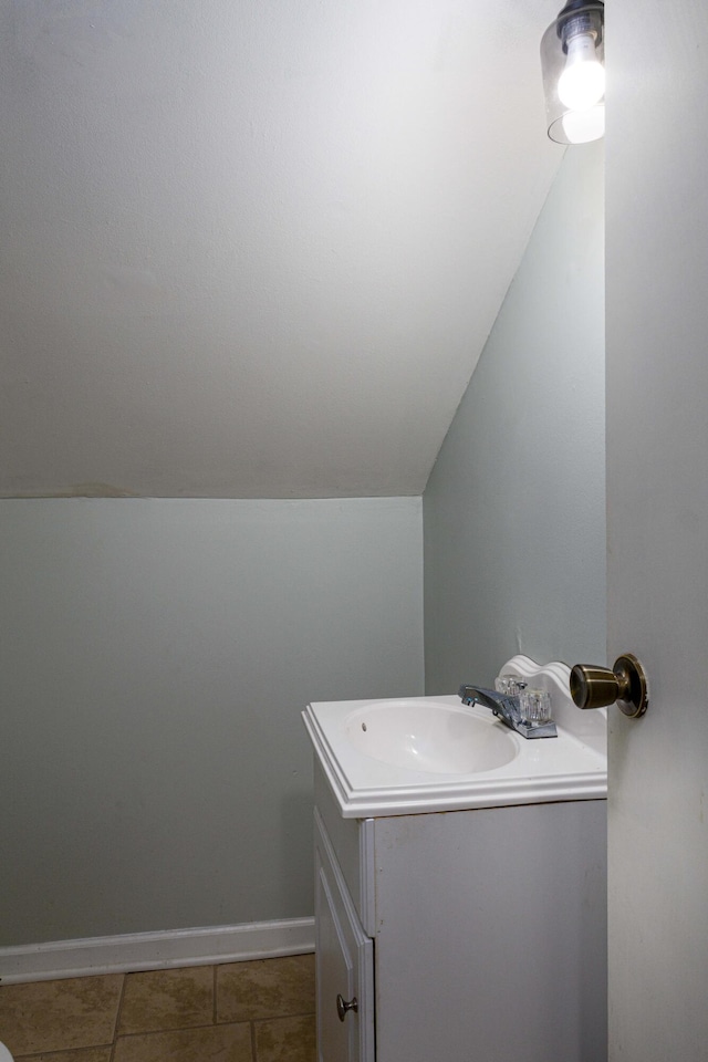 bathroom with tile patterned flooring, vanity, and vaulted ceiling