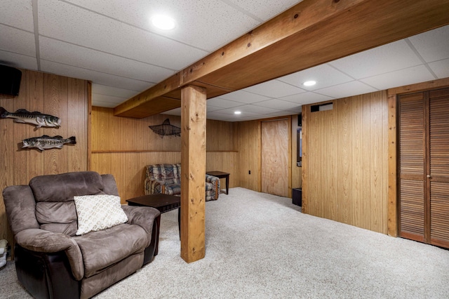 living area featuring light colored carpet, wooden walls, and a paneled ceiling