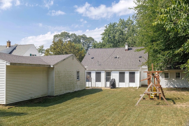 rear view of property with a yard and a playground