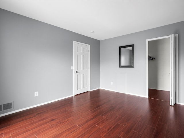 unfurnished bedroom with a walk in closet, dark hardwood / wood-style flooring, and a closet