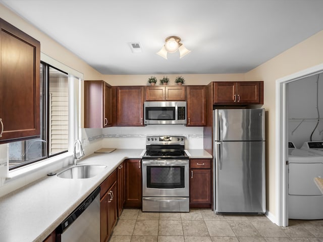 kitchen with washing machine and clothes dryer, stainless steel appliances, sink, and light tile patterned floors