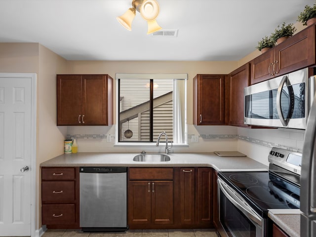 kitchen featuring light tile patterned flooring, sink, decorative backsplash, ceiling fan, and stainless steel appliances