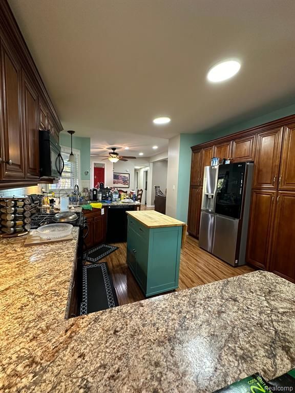 kitchen featuring butcher block counters, stainless steel fridge with ice dispenser, light hardwood / wood-style floors, and a center island