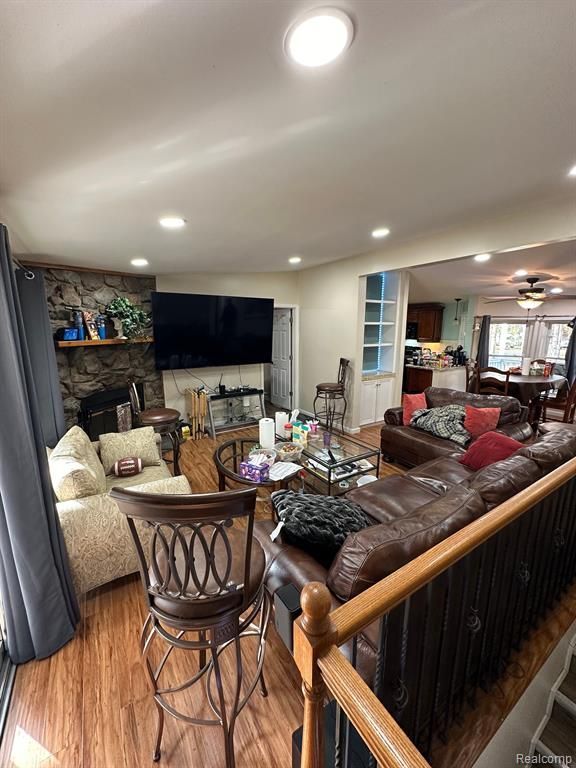 living room featuring ceiling fan, a fireplace, and light hardwood / wood-style flooring