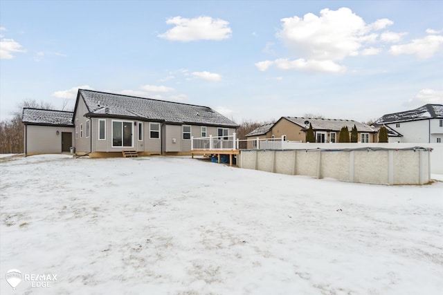 snow covered back of property with a covered pool