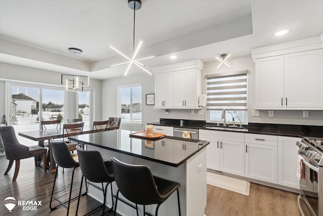 kitchen featuring sink, a breakfast bar, appliances with stainless steel finishes, hanging light fixtures, and white cabinets