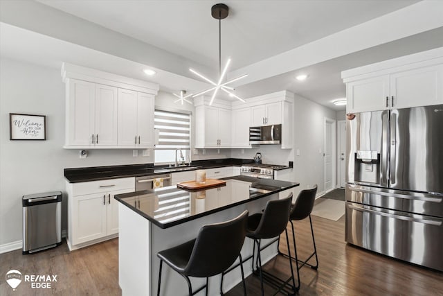 kitchen with a kitchen island, pendant lighting, sink, white cabinets, and stainless steel appliances