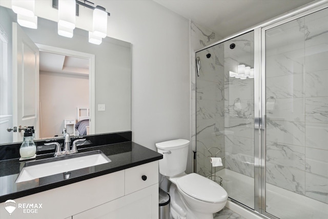 bathroom featuring a shower with door, vanity, and toilet