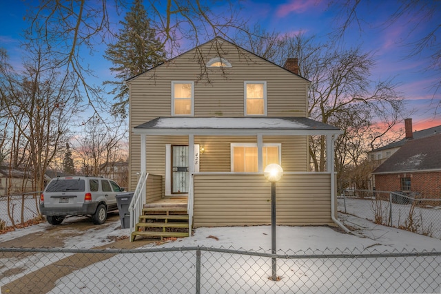 back house at dusk featuring a porch