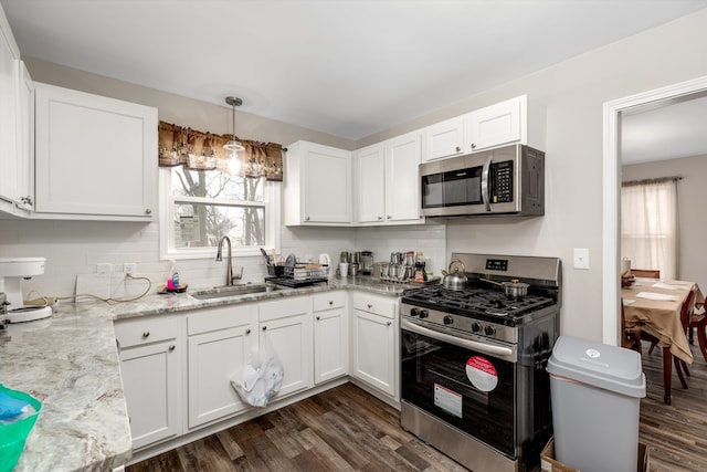 kitchen with pendant lighting, stainless steel appliances, sink, and white cabinets