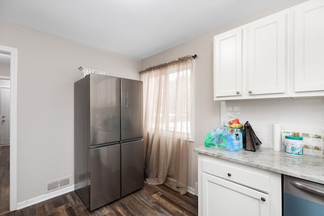 kitchen with white cabinetry, light stone counters, stainless steel refrigerator, dark hardwood / wood-style floors, and backsplash