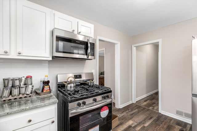 kitchen with backsplash, stainless steel appliances, light stone counters, white cabinets, and dark hardwood / wood-style flooring