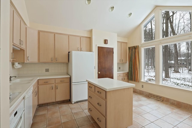 kitchen featuring a kitchen island, light brown cabinetry, sink, light tile patterned floors, and white appliances