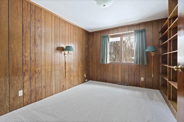 empty room featuring carpet flooring and wooden walls