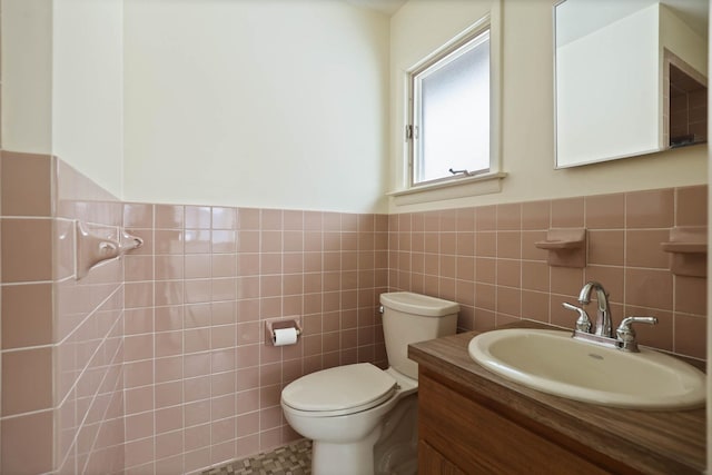 bathroom with vanity, toilet, and tile walls