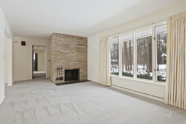 unfurnished living room with a baseboard radiator, a brick fireplace, and light carpet