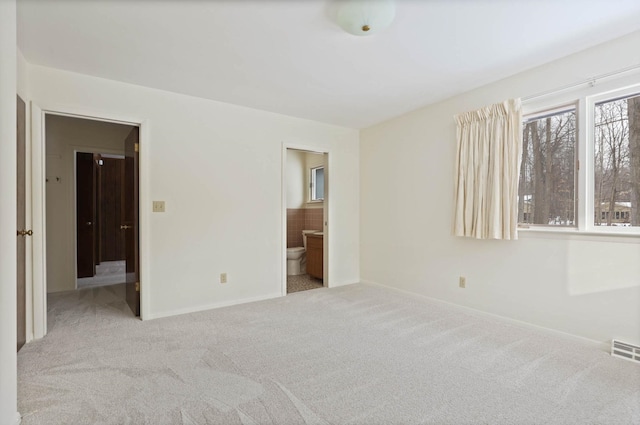 unfurnished bedroom featuring ensuite bathroom and light carpet