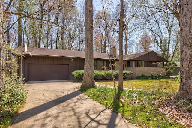 view of front facade featuring a garage, a chimney, and driveway