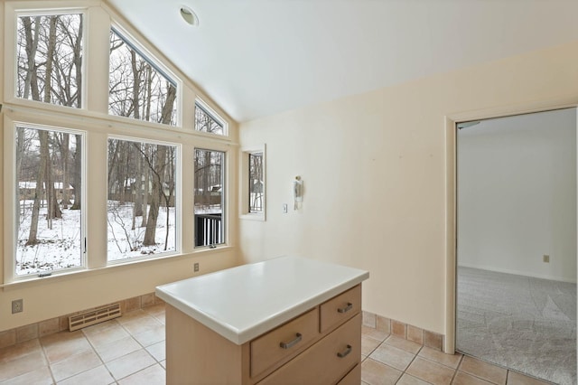 interior space featuring light countertops, high vaulted ceiling, a center island, light tile patterned floors, and visible vents