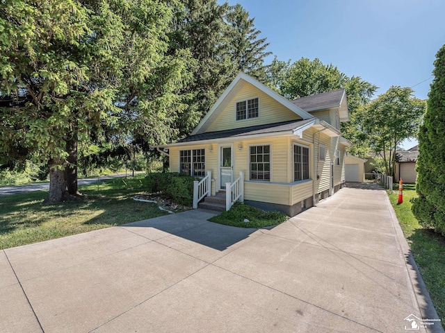 view of front of property featuring a garage, an outdoor structure, and a front lawn