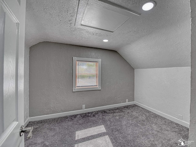 bonus room with dark carpet, vaulted ceiling, and a textured ceiling