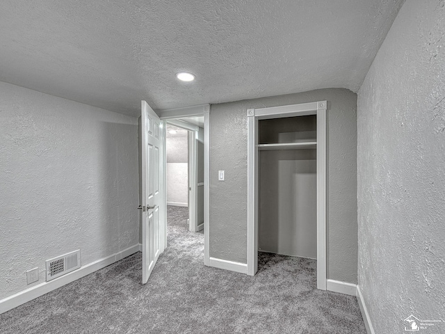 unfurnished bedroom featuring a closet, a textured ceiling, and carpet