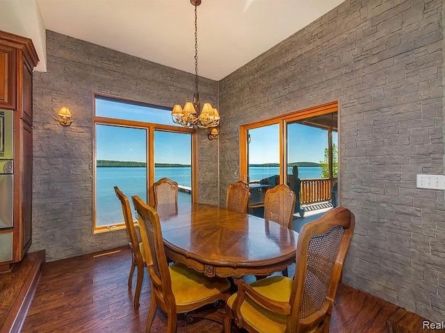 dining area featuring a water view, dark hardwood / wood-style floors, and a notable chandelier