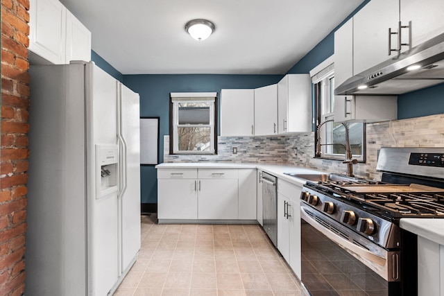 kitchen featuring light tile patterned flooring, appliances with stainless steel finishes, tasteful backsplash, white cabinetry, and sink