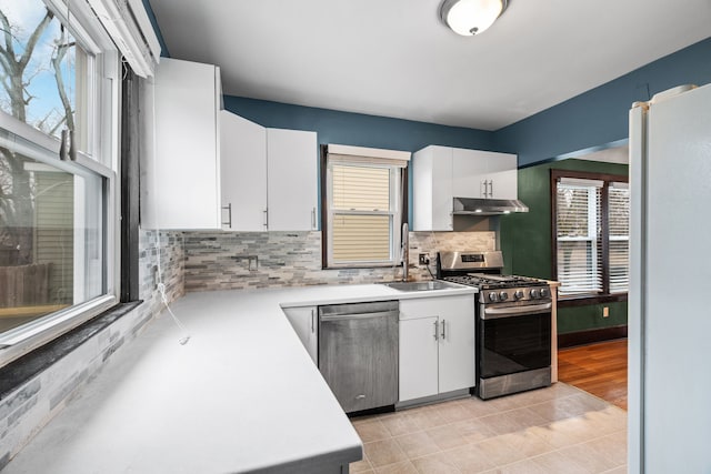 kitchen featuring light tile patterned flooring, sink, appliances with stainless steel finishes, decorative backsplash, and white cabinets