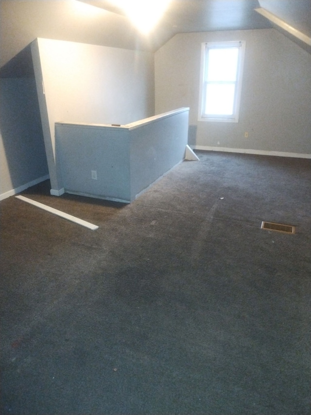 additional living space with lofted ceiling and dark carpet