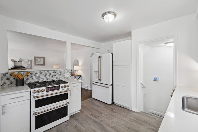 kitchen with white cabinetry, high quality appliances, and light hardwood / wood-style flooring