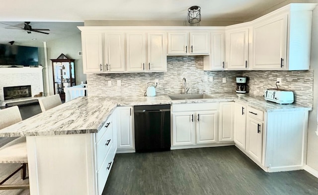 kitchen with white cabinetry, black dishwasher, sink, and a breakfast bar area