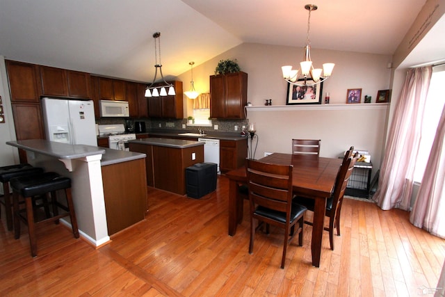 kitchen with hanging light fixtures, a center island, white appliances, and light hardwood / wood-style floors