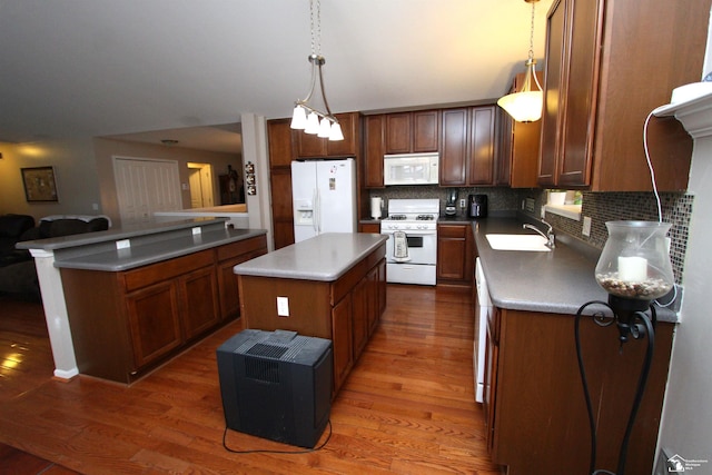 kitchen featuring dark wood-type flooring, sink, decorative light fixtures, a kitchen island, and white appliances