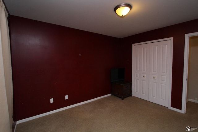 unfurnished bedroom with light colored carpet and a closet