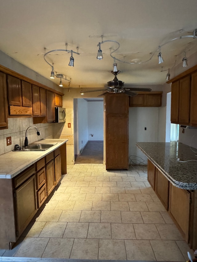 kitchen featuring ceiling fan, sink, and backsplash