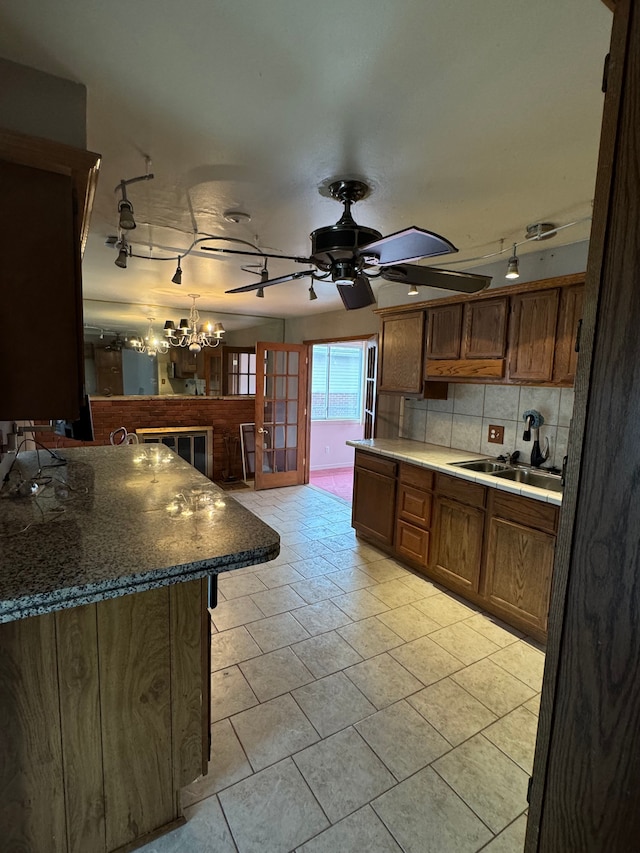 kitchen with ceiling fan with notable chandelier, decorative light fixtures, sink, and decorative backsplash