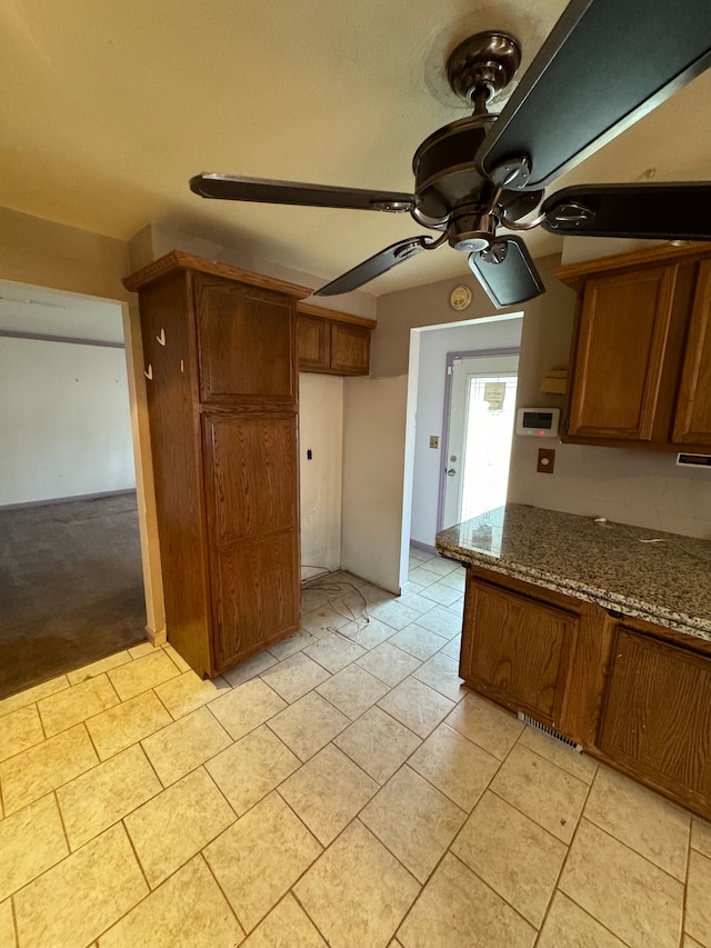 kitchen featuring dark stone countertops, light tile patterned floors, and ceiling fan