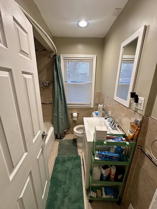 full bathroom featuring shower / bathtub combination with curtain, tile walls, vanity, tile patterned floors, and toilet