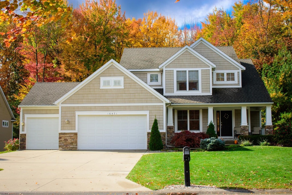 craftsman inspired home with a garage, a front yard, and covered porch